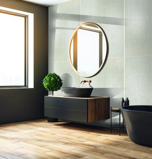 Modern bathroom with black freestanding bathtub, wooden vanity, and round mirror.